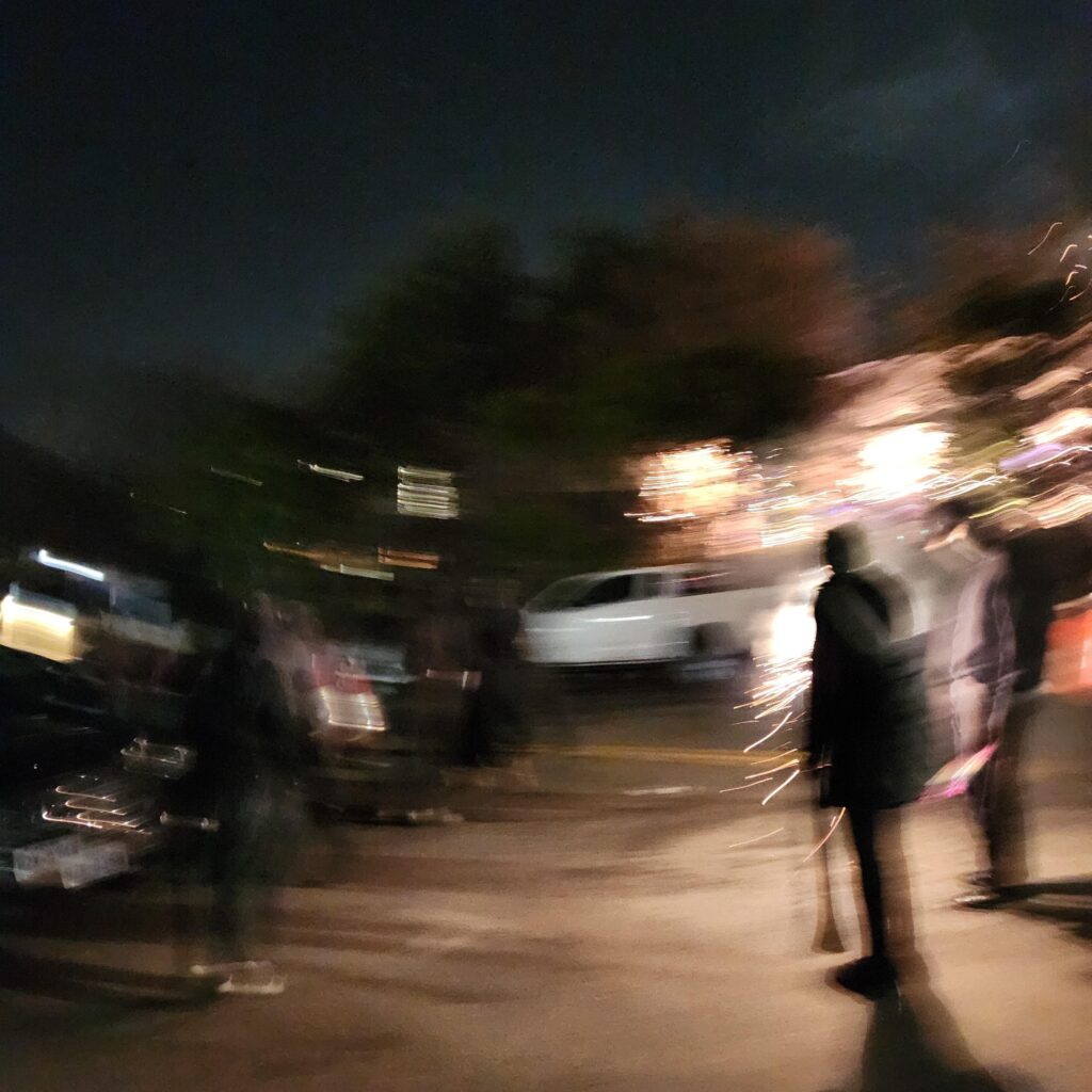 a blurry photo of a crowd with fireworks and in black masks