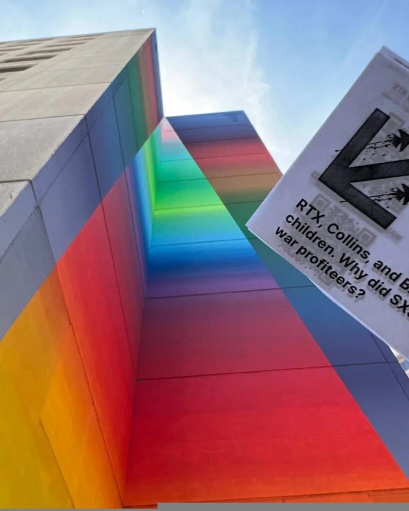 Flyers descending towards the camera in front of a rainbow colored mural